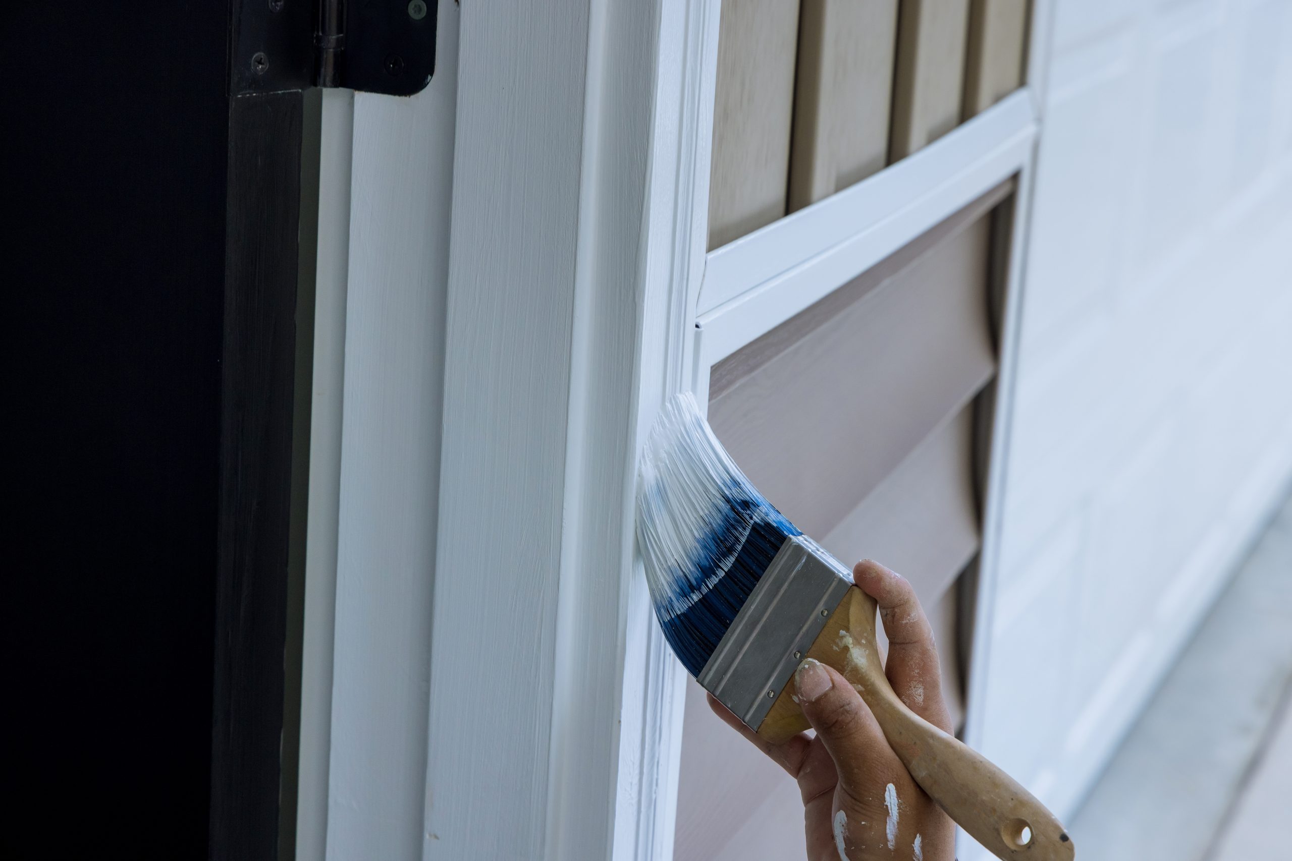 Paintbrush are used by a carpenter to paint wooden moldings on door trims