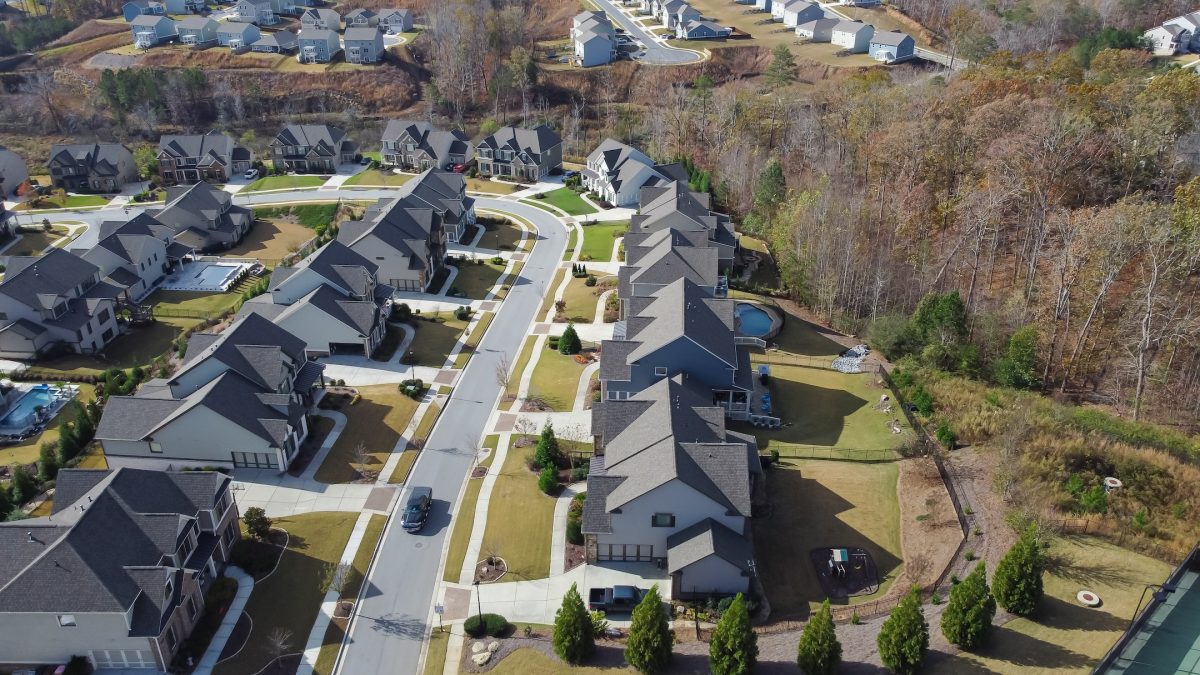 Row of new developments houses in master planned subdivision with lush green trees and natural trails outside Atlanta, Georgia, USA. Aerial view urban sprawl suburban residential neighborhood